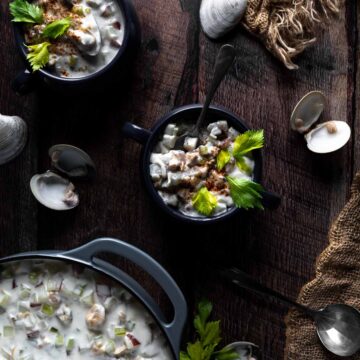 Overhead photo of New England Clam Chowder garnished with paprika and celery leaves.