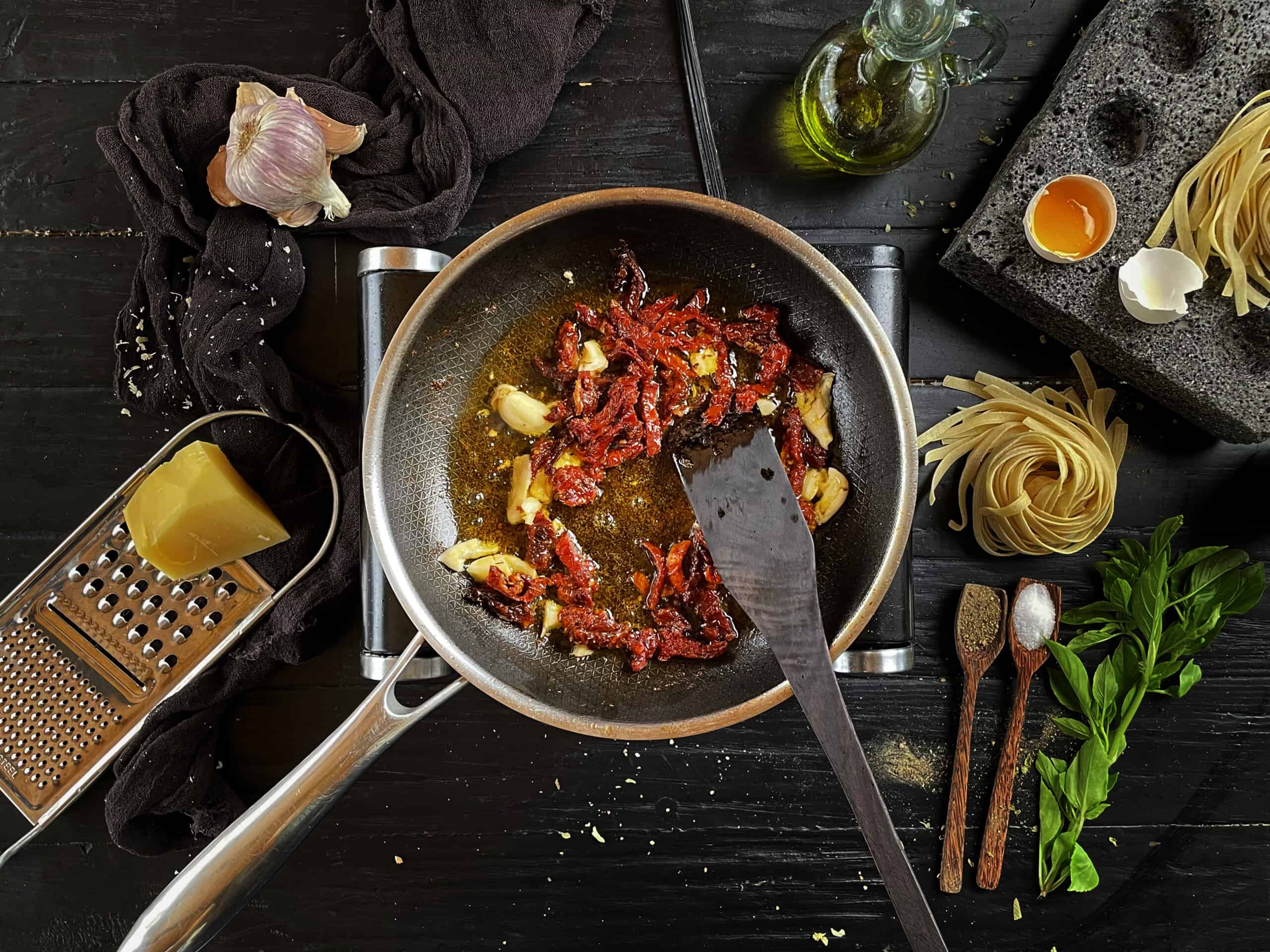 Sun dried tomatoes and garlic sautéing in a pan