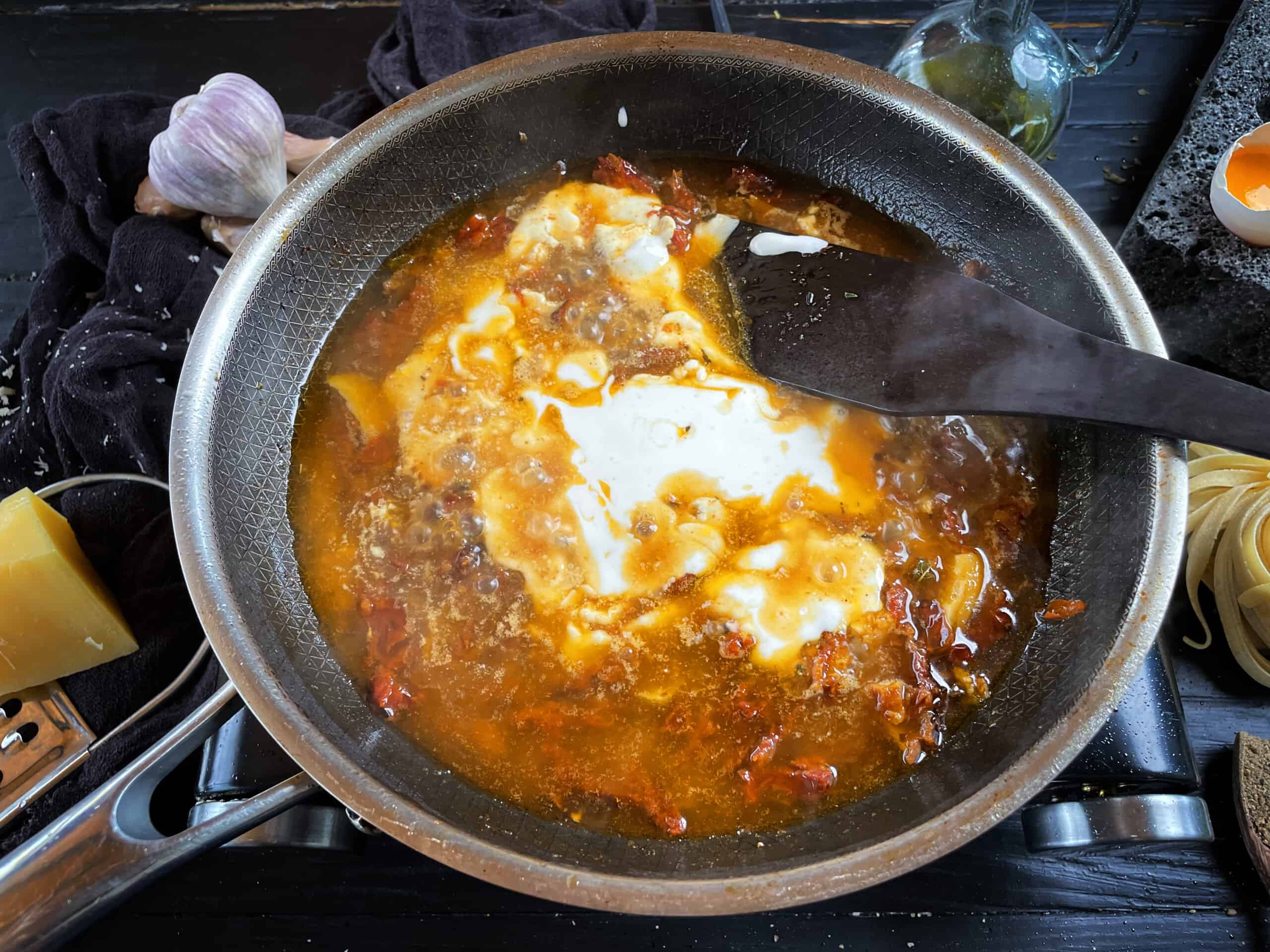 Cream being stirred into the sun dried tomato sauce