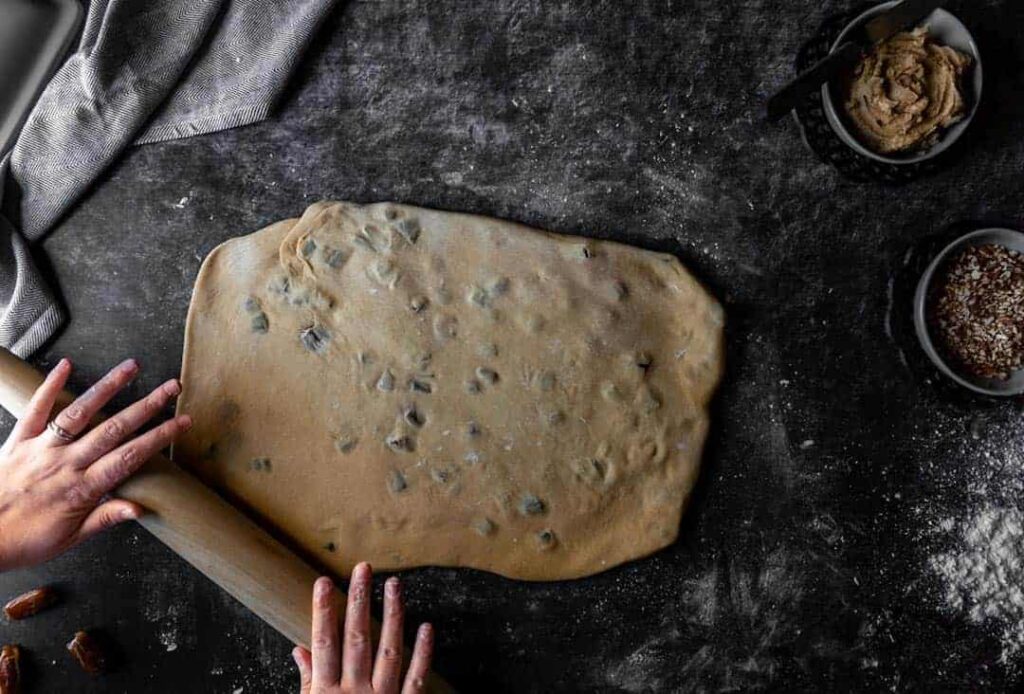 Using a rolling pin to shape the molasses dough into a large rectangle