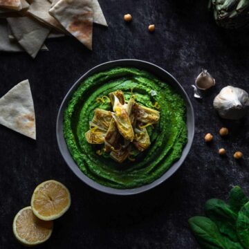 Spinach hummus scene with pita triangles, lemons and garlic