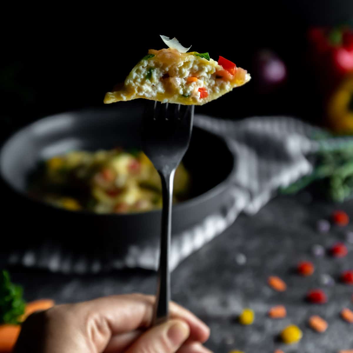 Half of a ravioli filled with ricotta and Primavera vegetables on a fork
