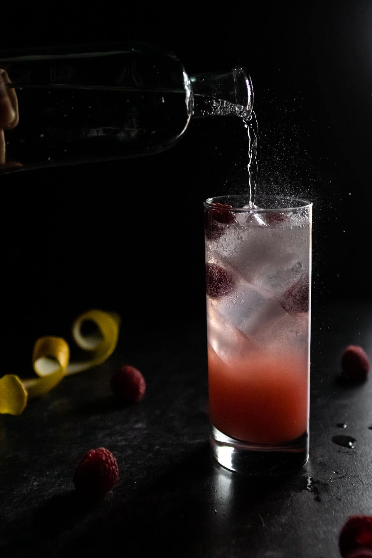 Soda water being poured into a Raspberry Lychee Mocktail