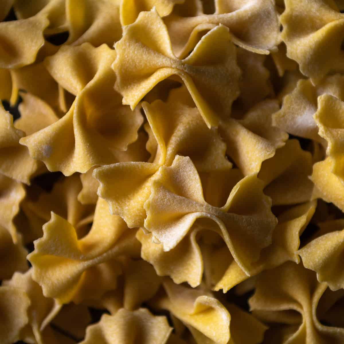 A close-up macro shot of a pile of fresh made farfalle