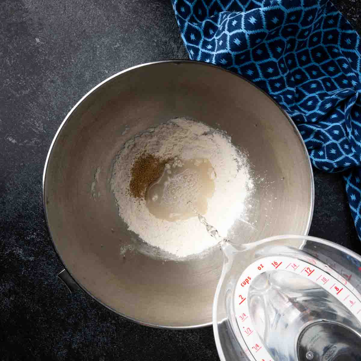 Combining ingredients to create a sponge for homemade pita bread.