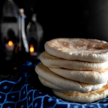 A stack of fluffy pita on a Moroccan patterned blue linen.