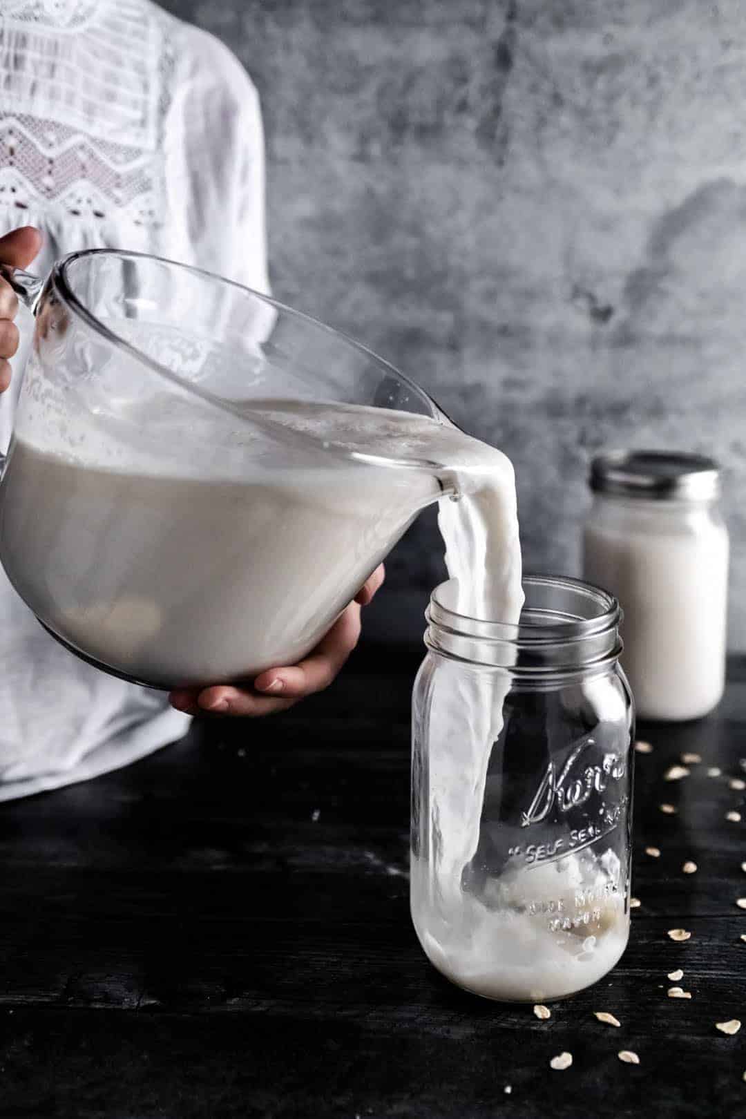 a woman pouring freshly made oat milk