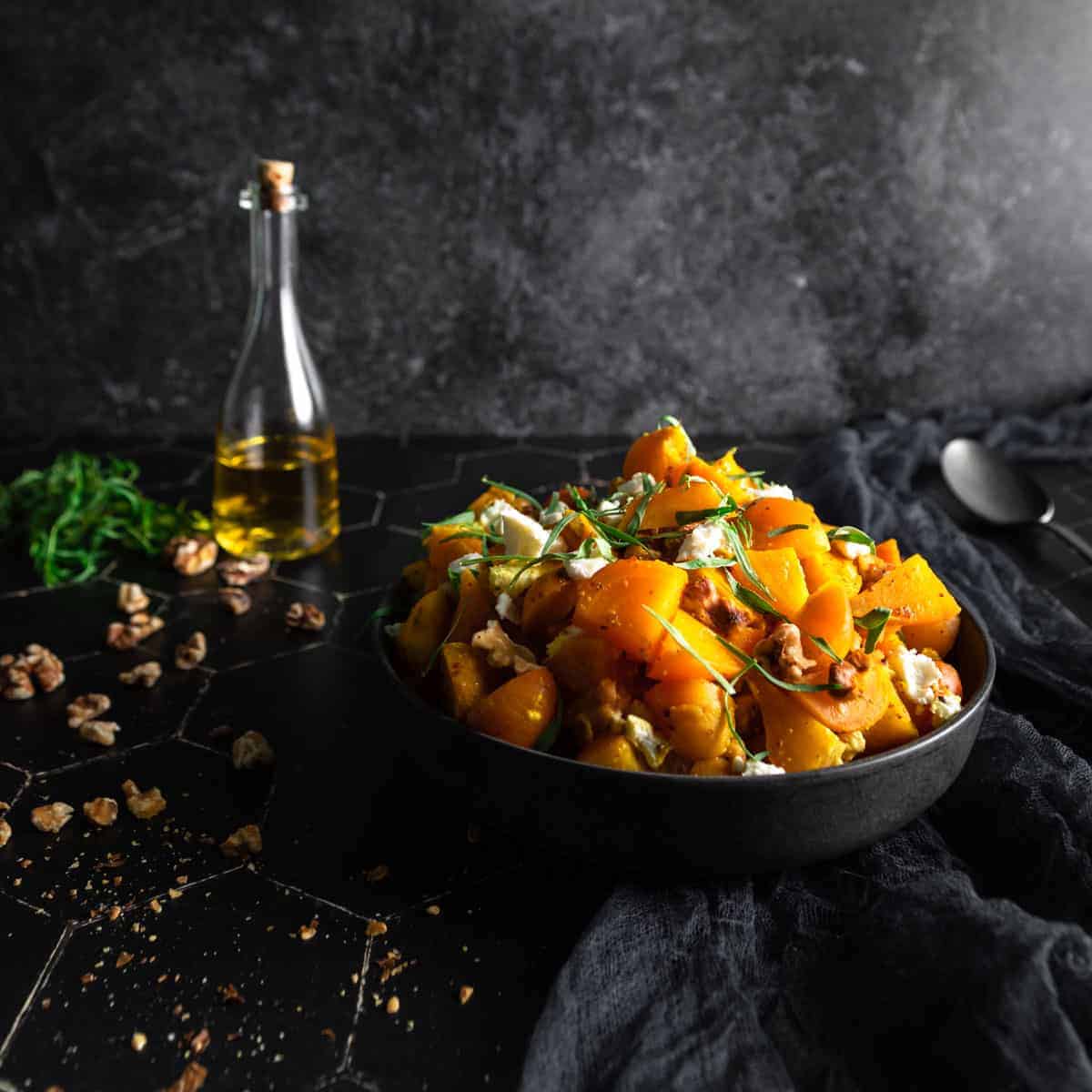 A big bowl of golden beet salad next to chopped walnuts a bunch of fresh tarragon and a small corked bottle of walnut oil.