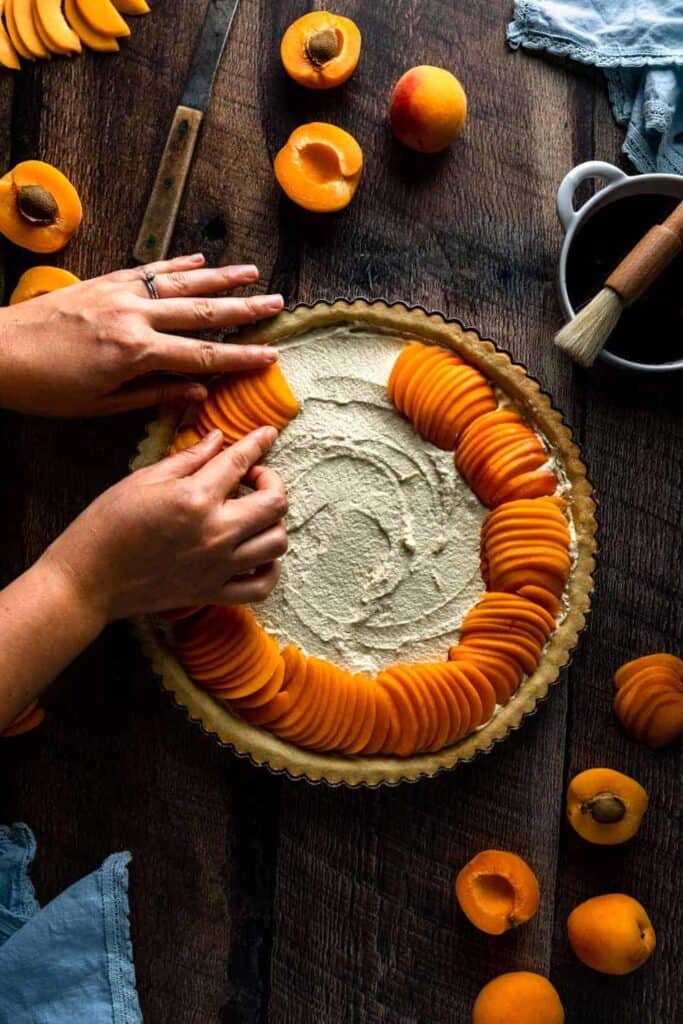 Arranging slices of apricots around the perimeter of the tart