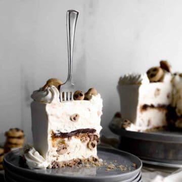 A slice of cookie dough ice cream cake with a layer of chocolate ganache in the center and a for sticking straight up form the slice