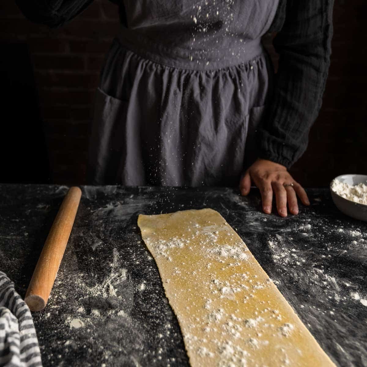 Dusting a sprinkle of flour over a sheet of pasta dough.