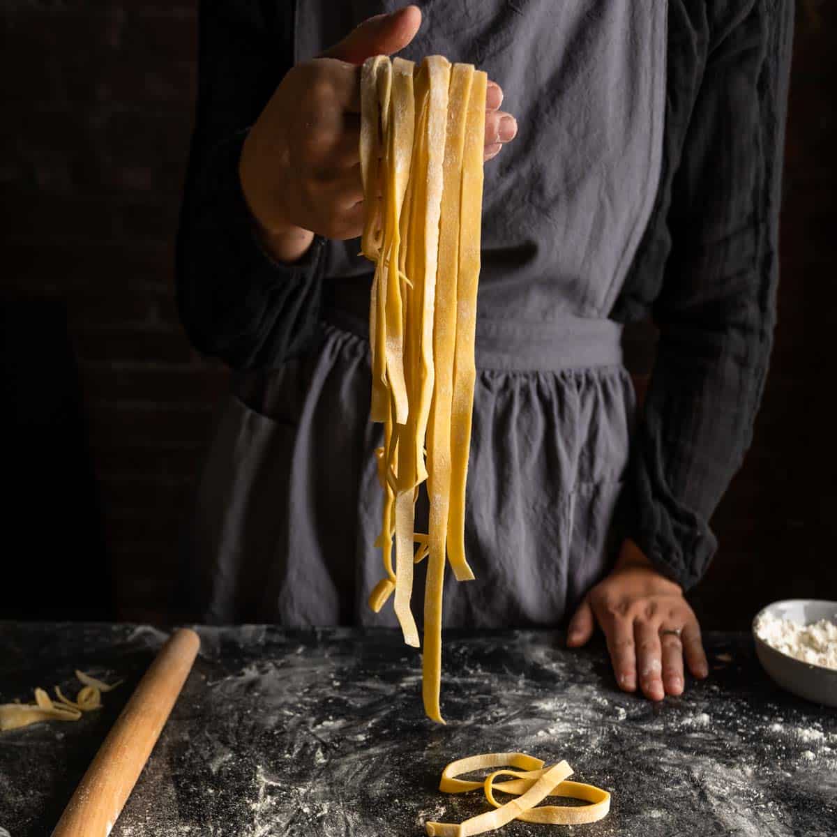 Man in apron making spaghetti with noodle cutter. Close-up pasta