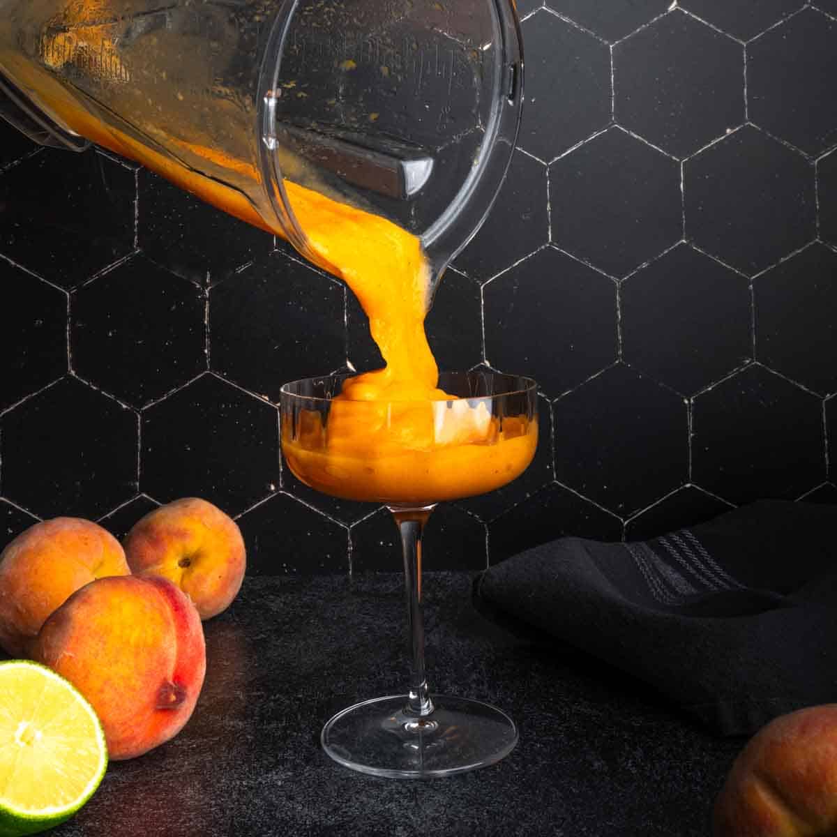 Pouring a frozen peach daiquiri from the blender into a coupe glass. 