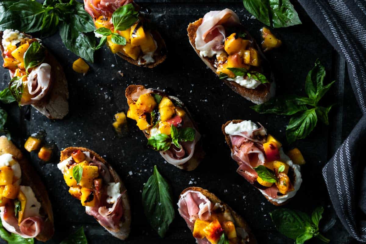 A board full of multiple peach Burrata Bruschetta crostini