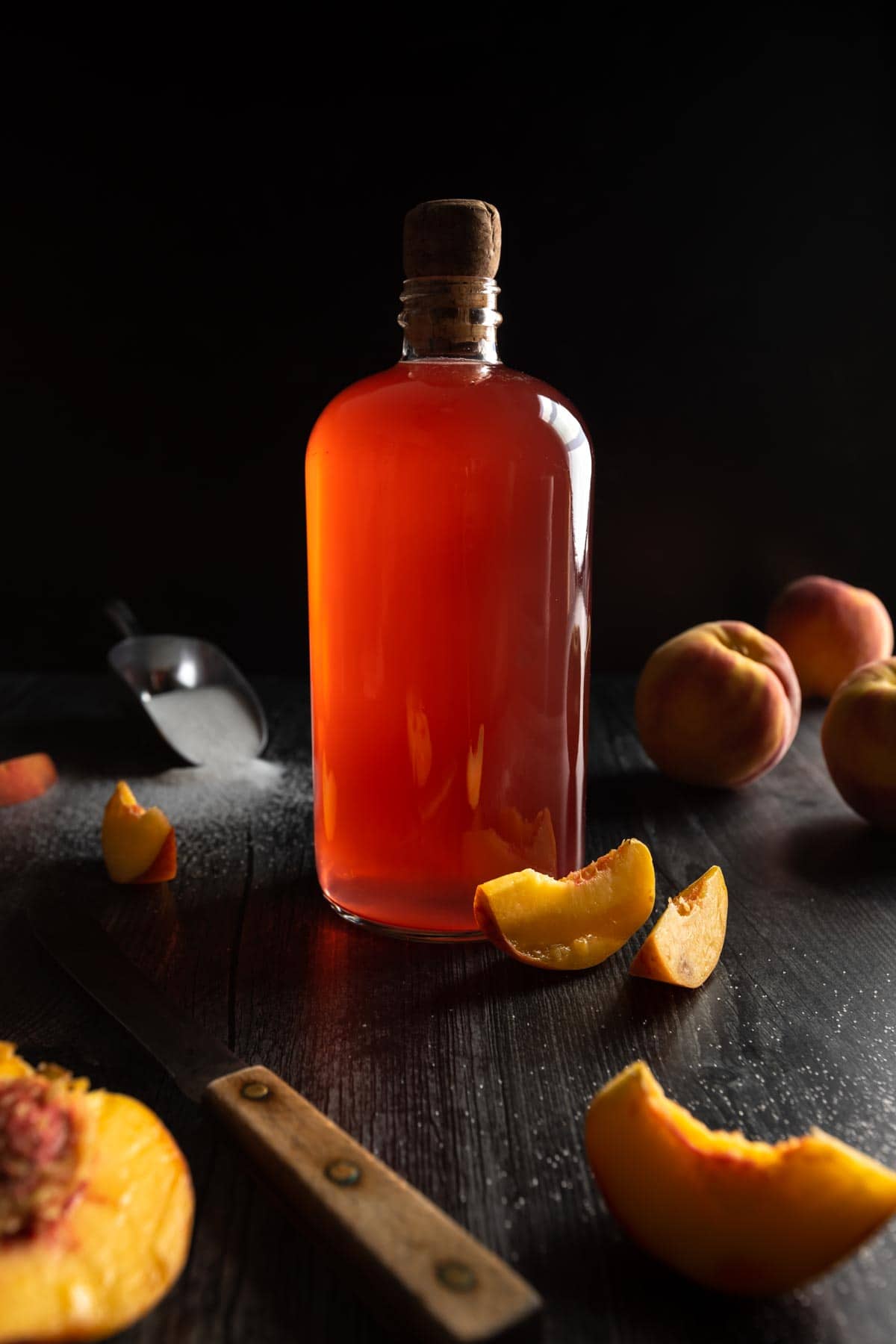 A jar of peach strip next to peach slices and a paring knife