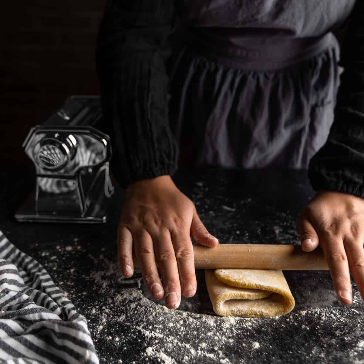 Rolling a piece of pasta dough that has been tri-folded, like a letter.