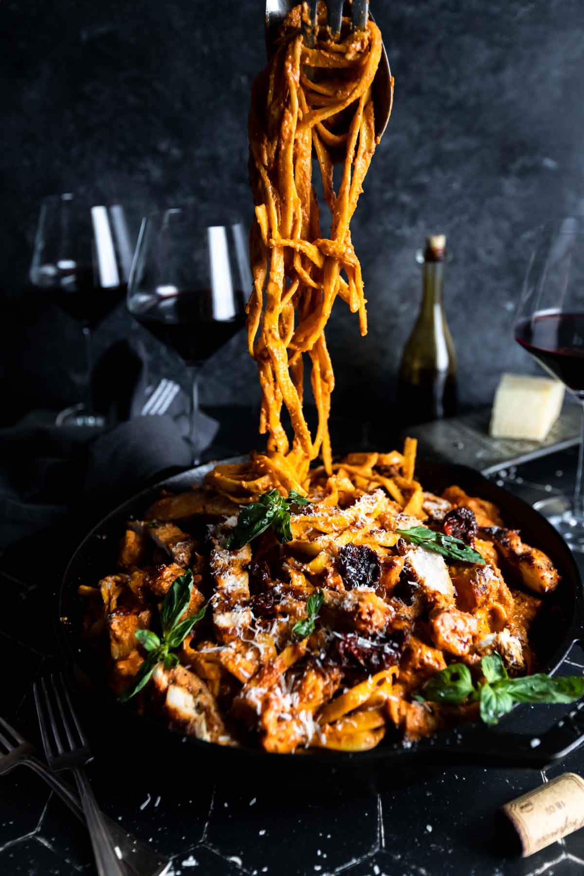 Pulling a portion of sun dried tomato Fettuccine Alfredo from a large skillet