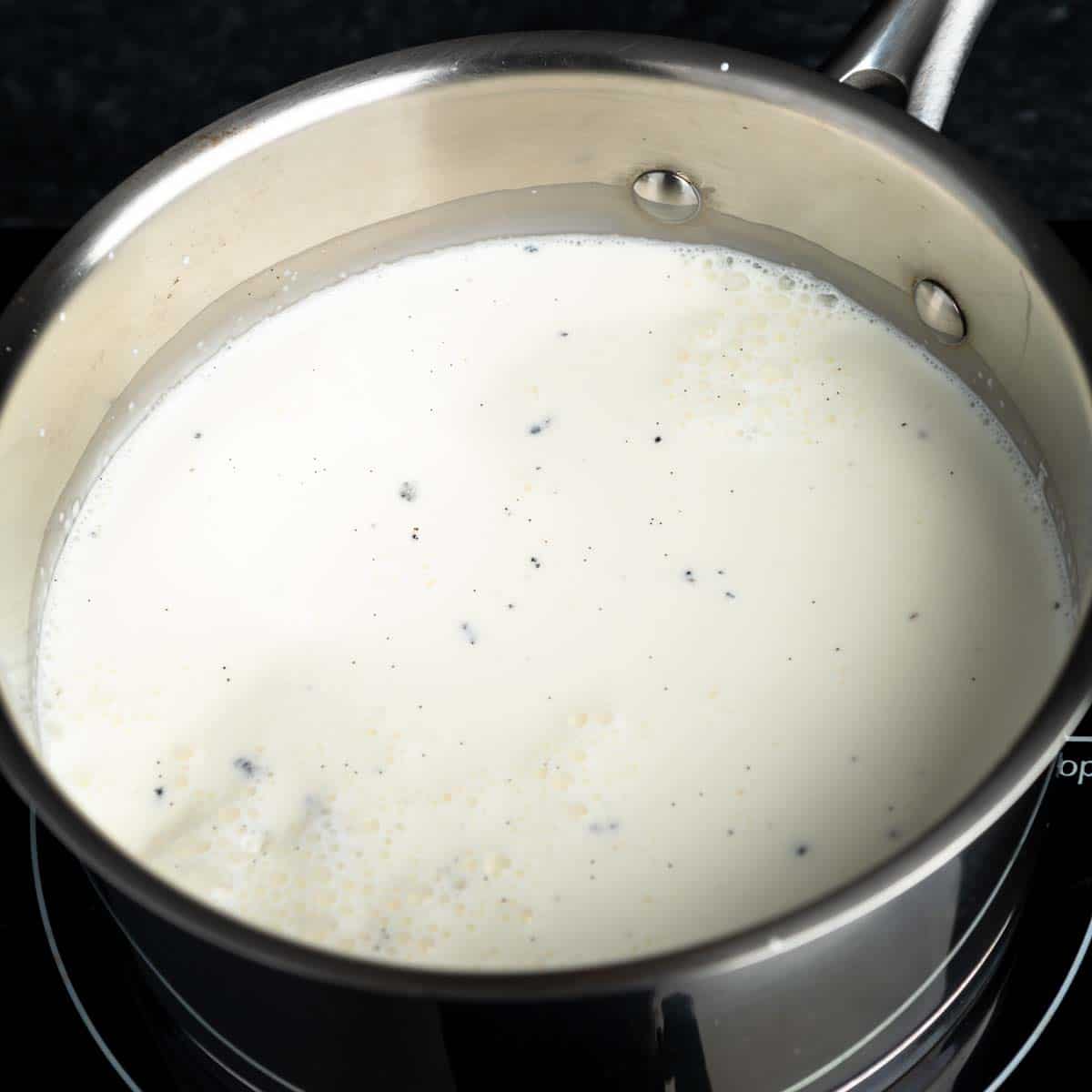 Vanilla bean, cream, milk and sugar heating in a pot