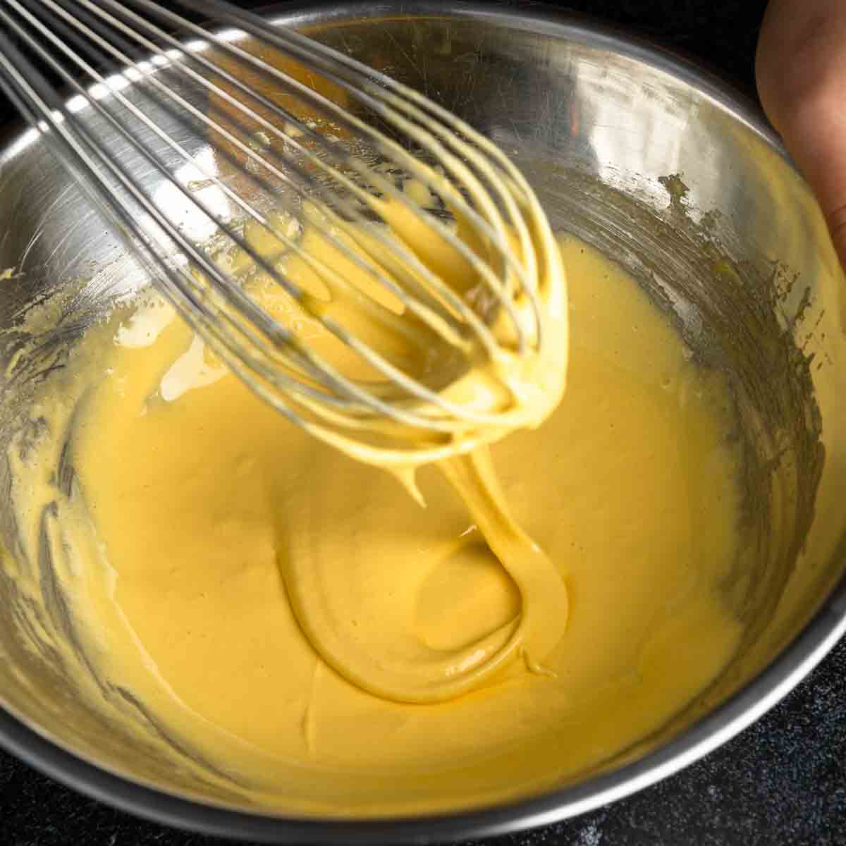 Whisked eggs and sugar falling from the whisk in ribbons