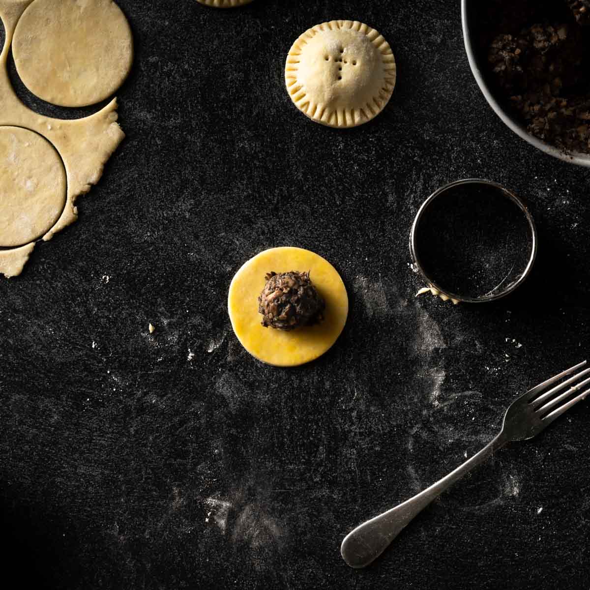 a small circle of pie dough topped with a Tablespoon of mushroom filling.