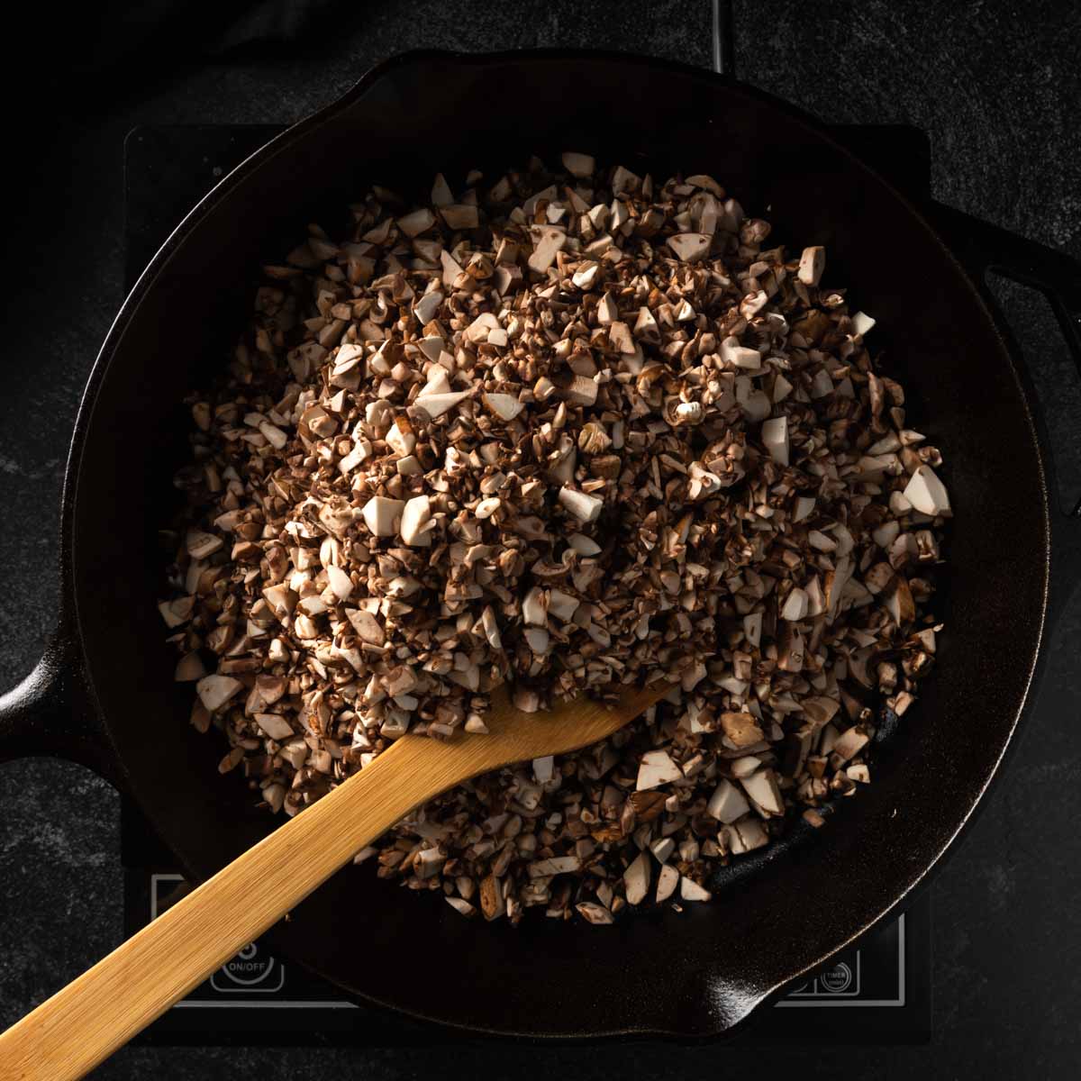 Raw, chopped mushrooms in a dry heated cast iron skillet