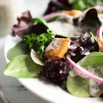 A close up shot of creamy poppyseed dressing on a green salad