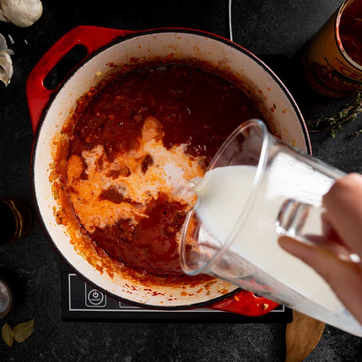 Pouring milk into the bolognese ragu sauce