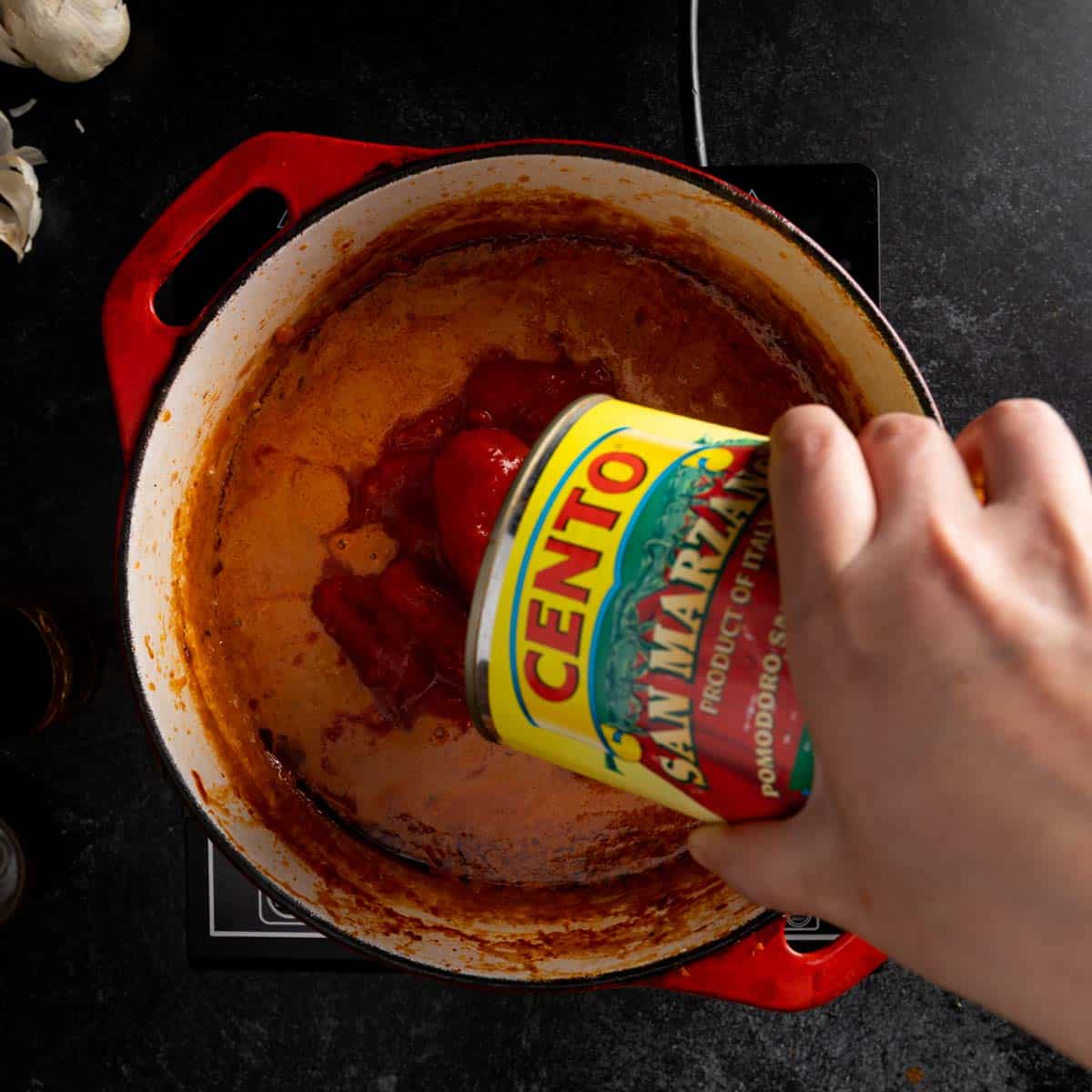 Adding a can of San Marzano tomatoes to the Ragu alla Bolognese.