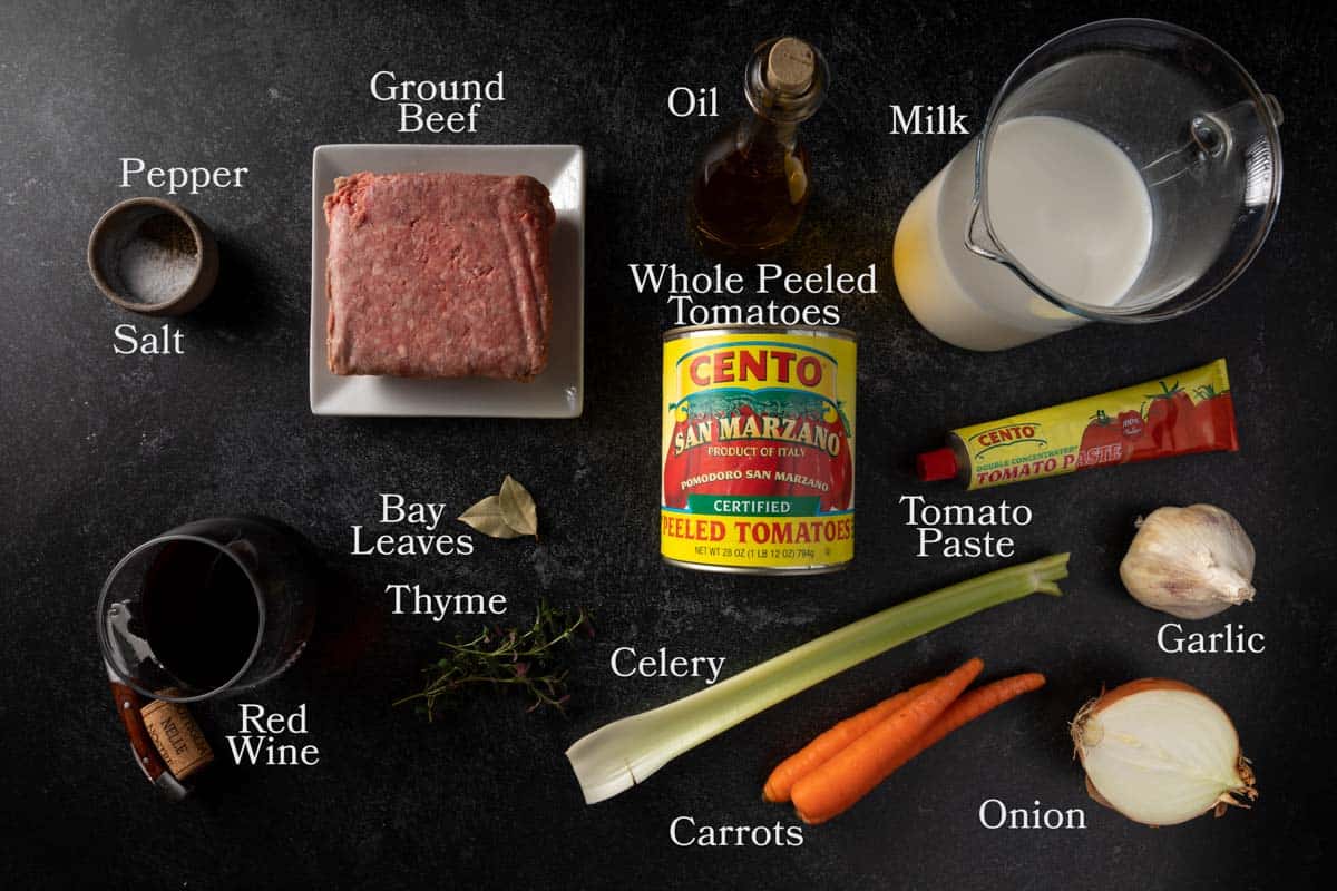 Ingredients needed for Ragu Alla Bolognese including carrot, onion, celery, garlic, olive oil, ground beef, tomato paste, San Marzano tomatoes, milk, wine, bay leaves, fresh thyme and salt and pepper. 