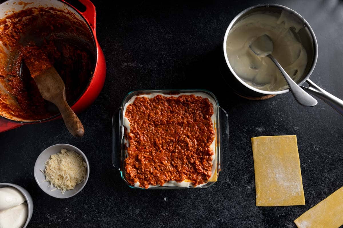 A lasagna pan layered with pasta, cream sauce and topped with a thick layer of Beef Bolognese
