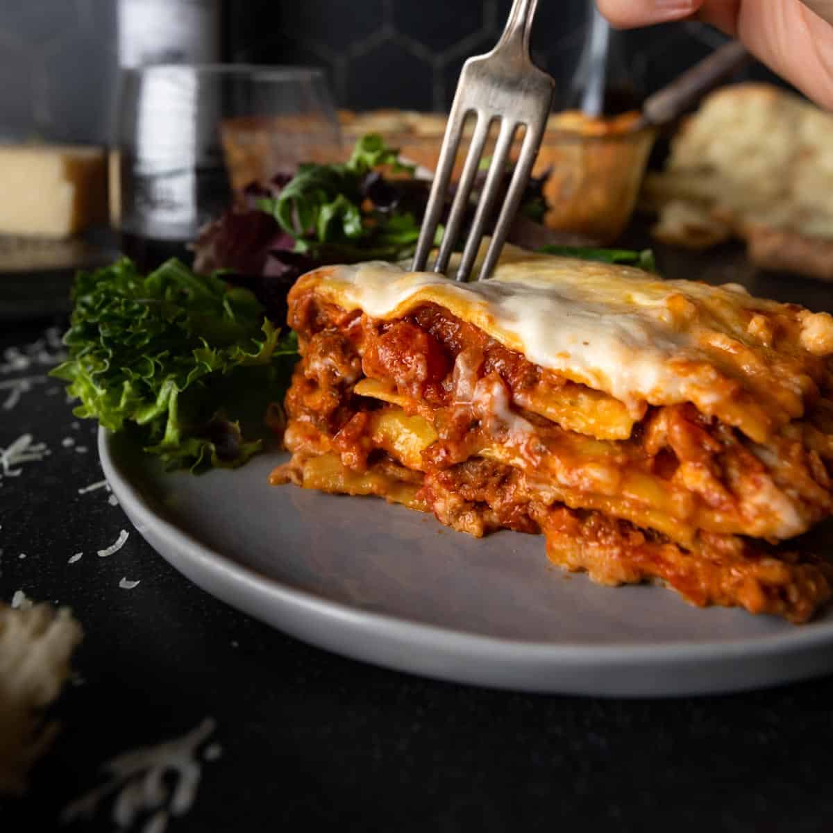 A fork going in for the first bite of lasagna al forno