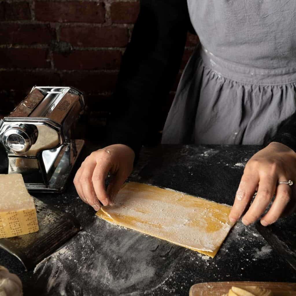 A couple of well floured pasta sheets being stacked directly over one another.