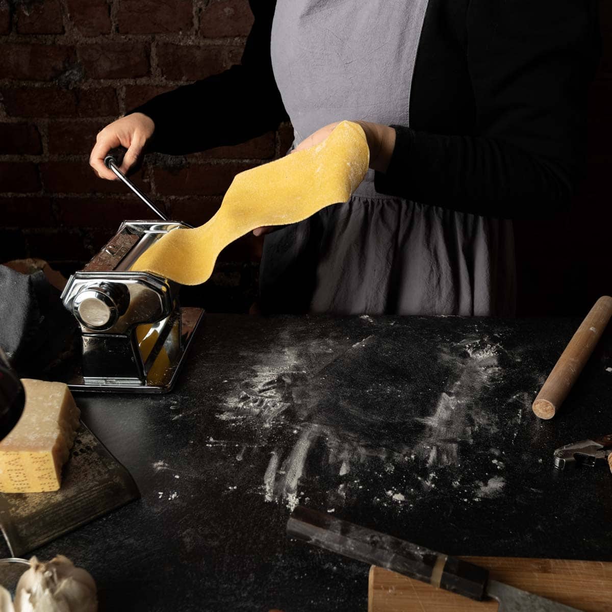 Rolling homemade semolina and egg pasta dough through a pasta machine