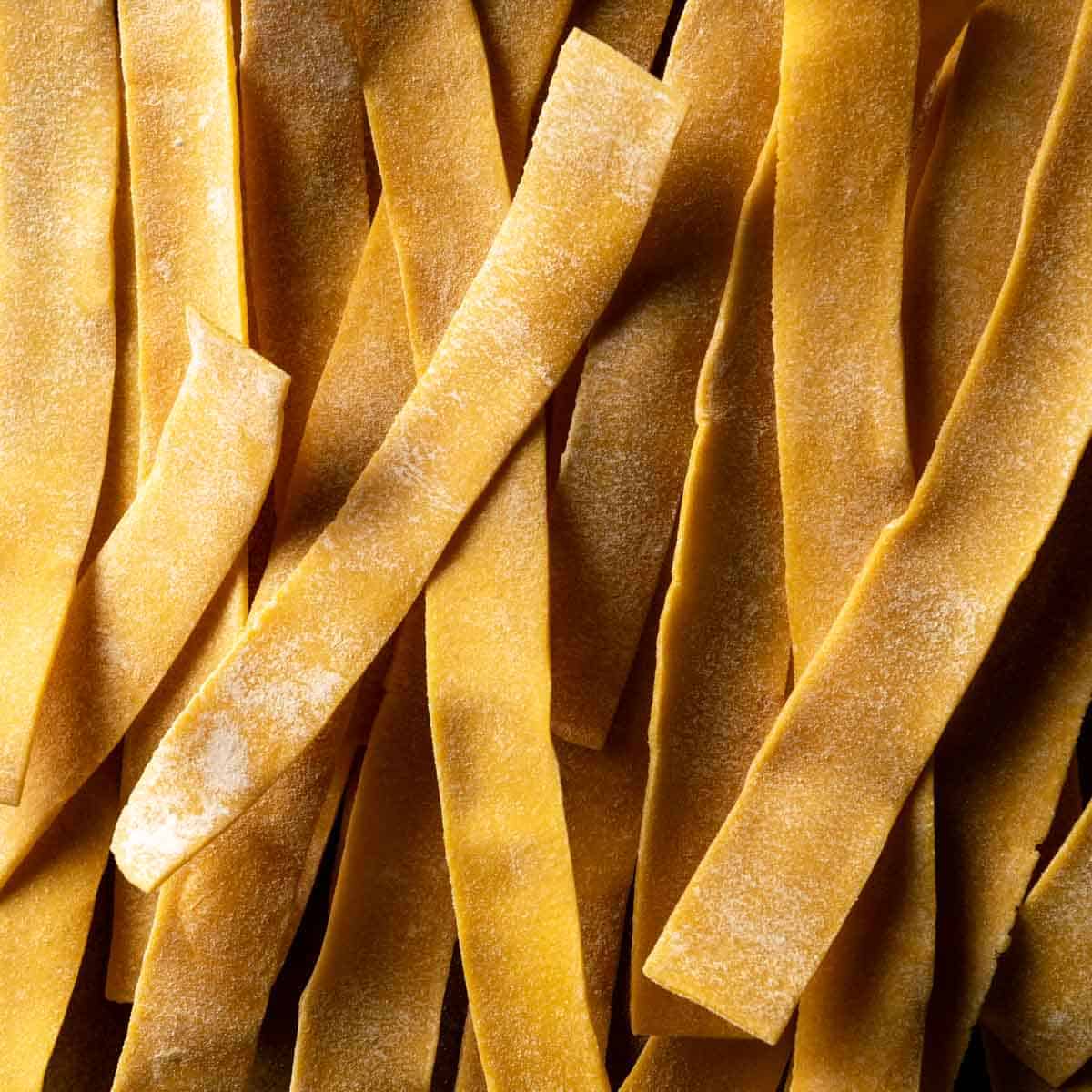 A close up photo of dried ribbons of pappardelle pasta.