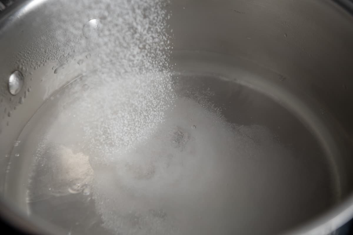 Adding sugar to a pot of boiling water