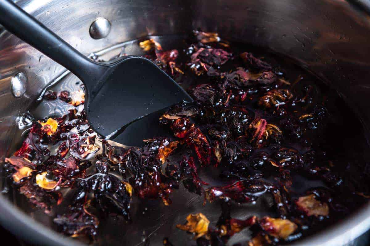 stirring dried hibiscus flowers into syrup.