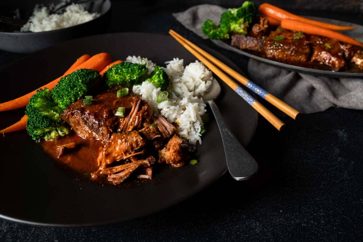 Braised Korean beef short ribs on a plate with white rice and steamed vegetables