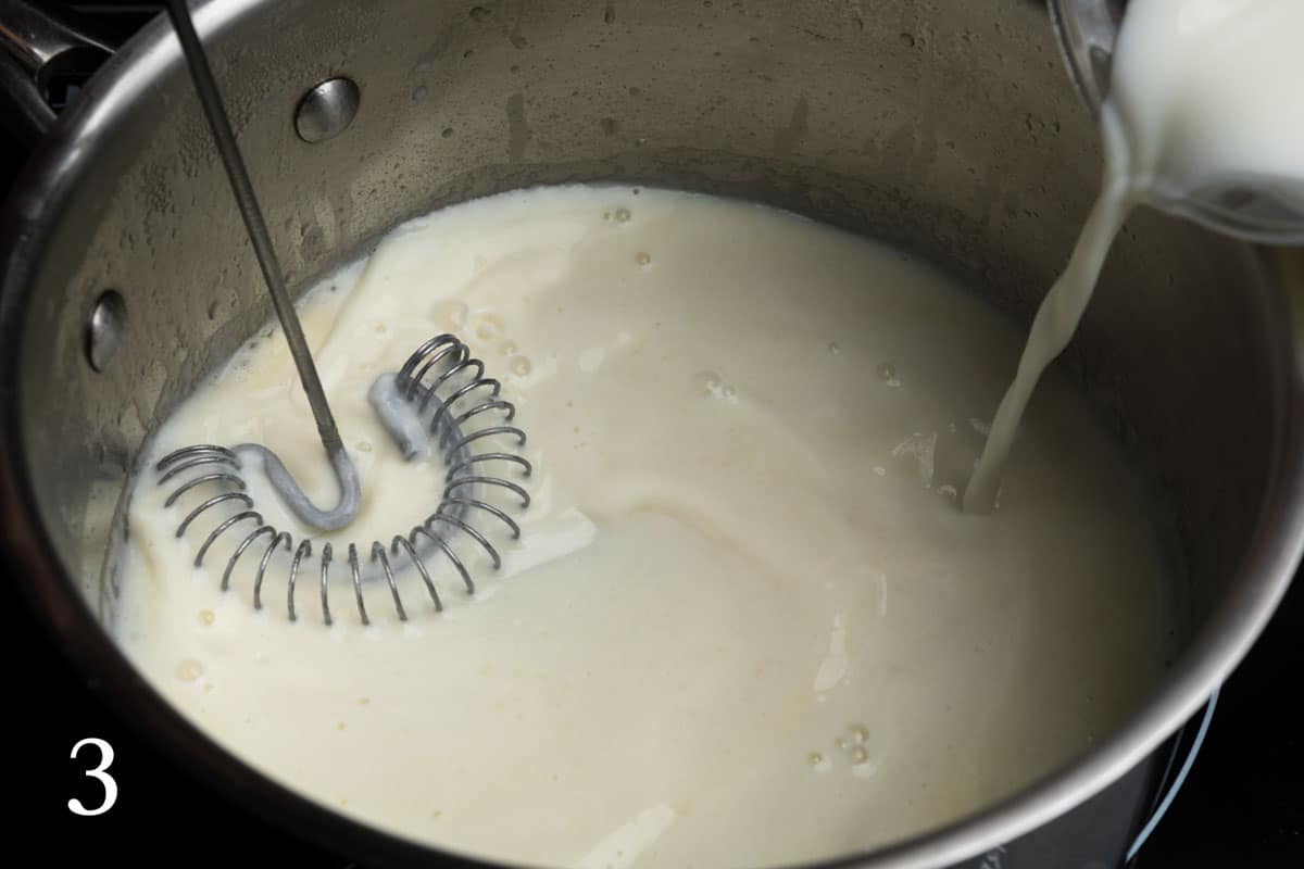 Streaming milk into the roux while whisking