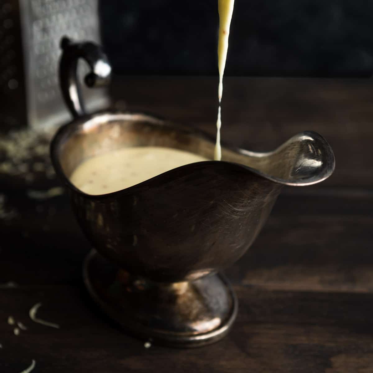 Pouring cheese sauce into an ornate gravy boat