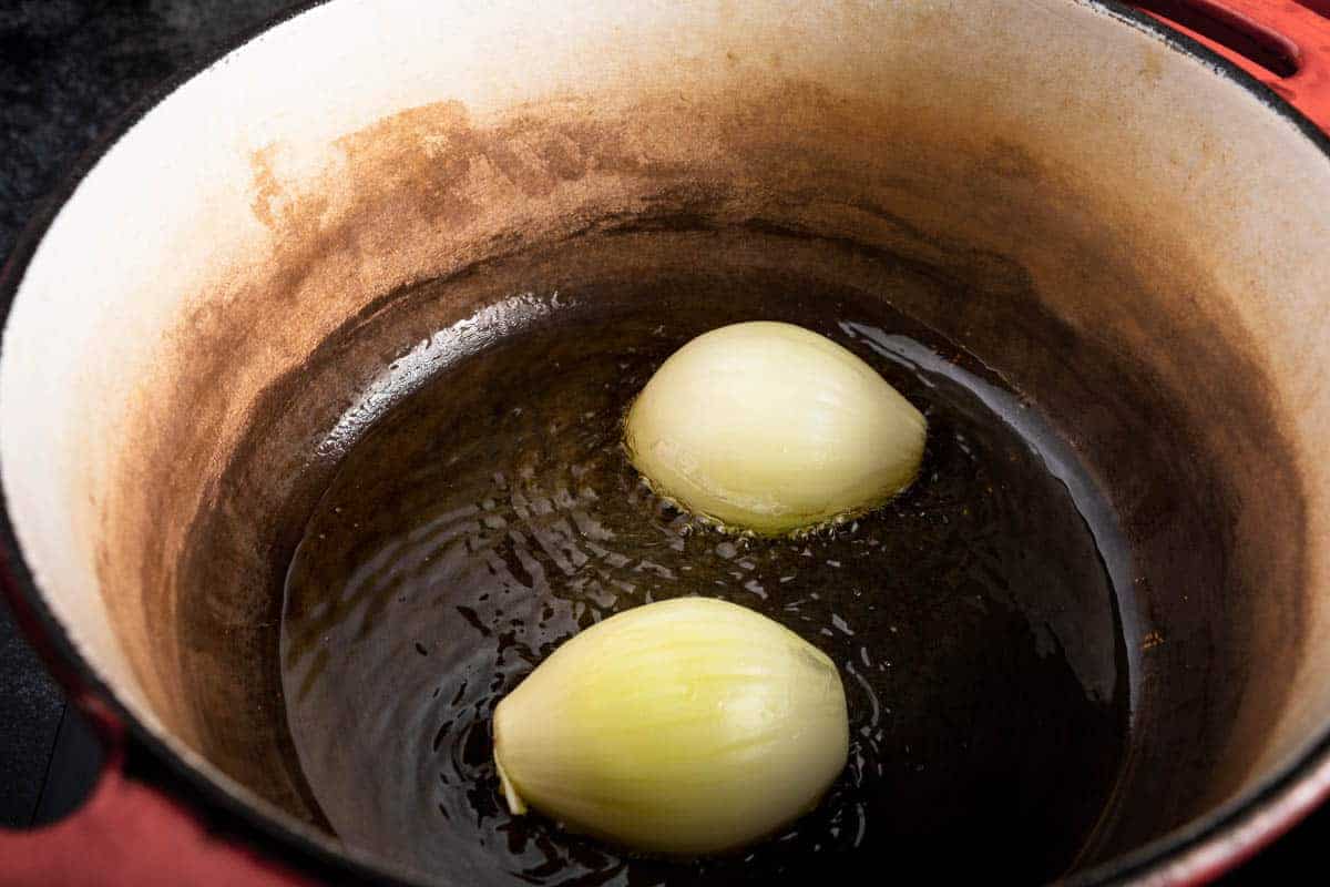 halved onion searing in shimmering oil in a dutch oven