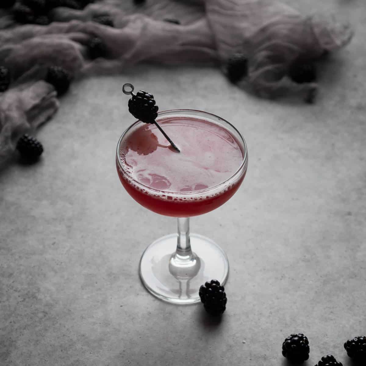 A blackberry bee's knees cocktail in a coupe 