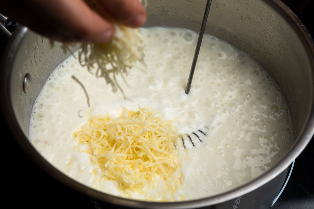 Sprinkling shredded Swiss cheese into the white sauce