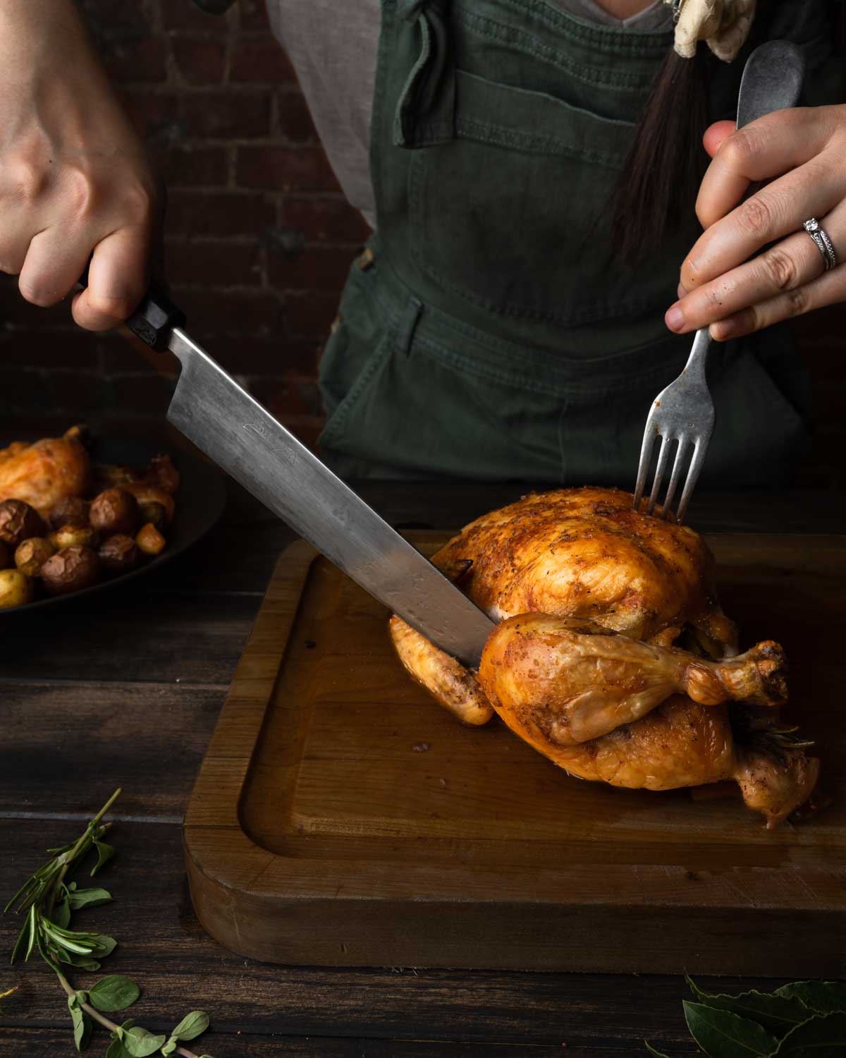 A sharp knife slicing the hind quarters off of the chicken.