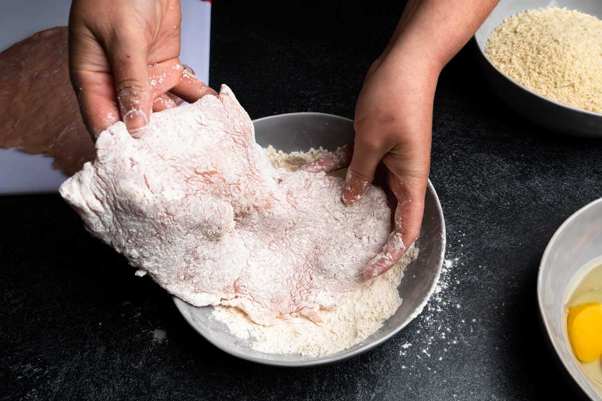 Coating a pounded pork cutlet in seasoned flour