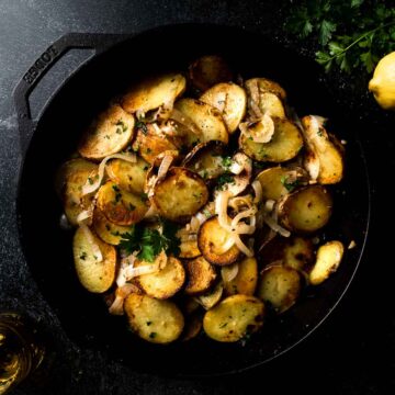 big skillet filled with potatoes Lyonnaise garnished with parsley