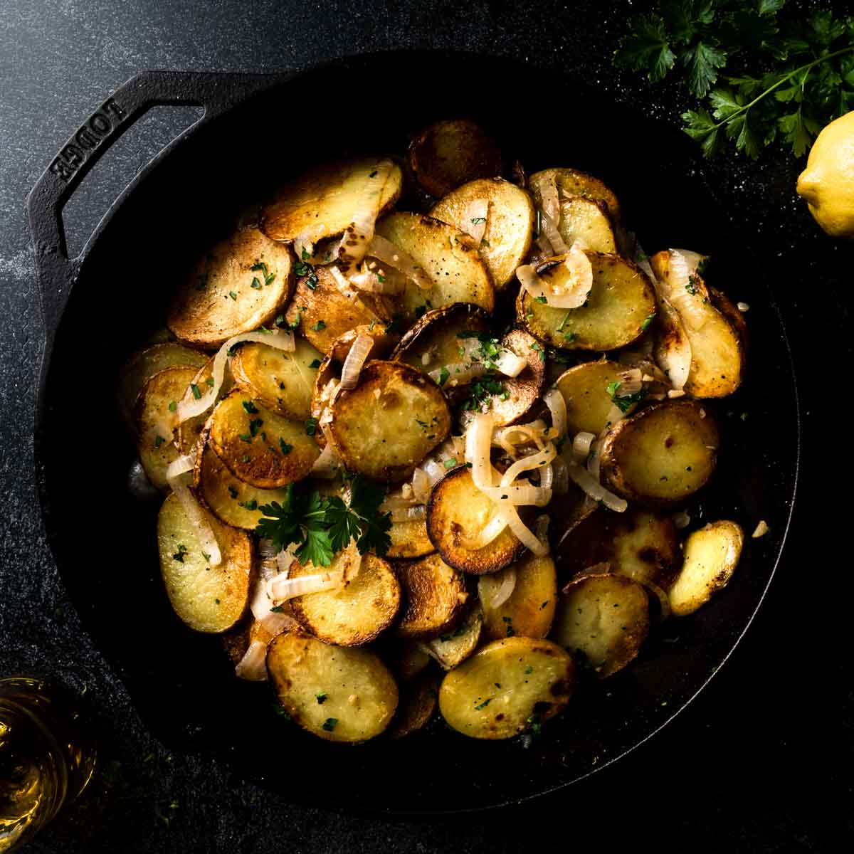 A big skillet filled with Lyonnaise potatoes garnished with parsley