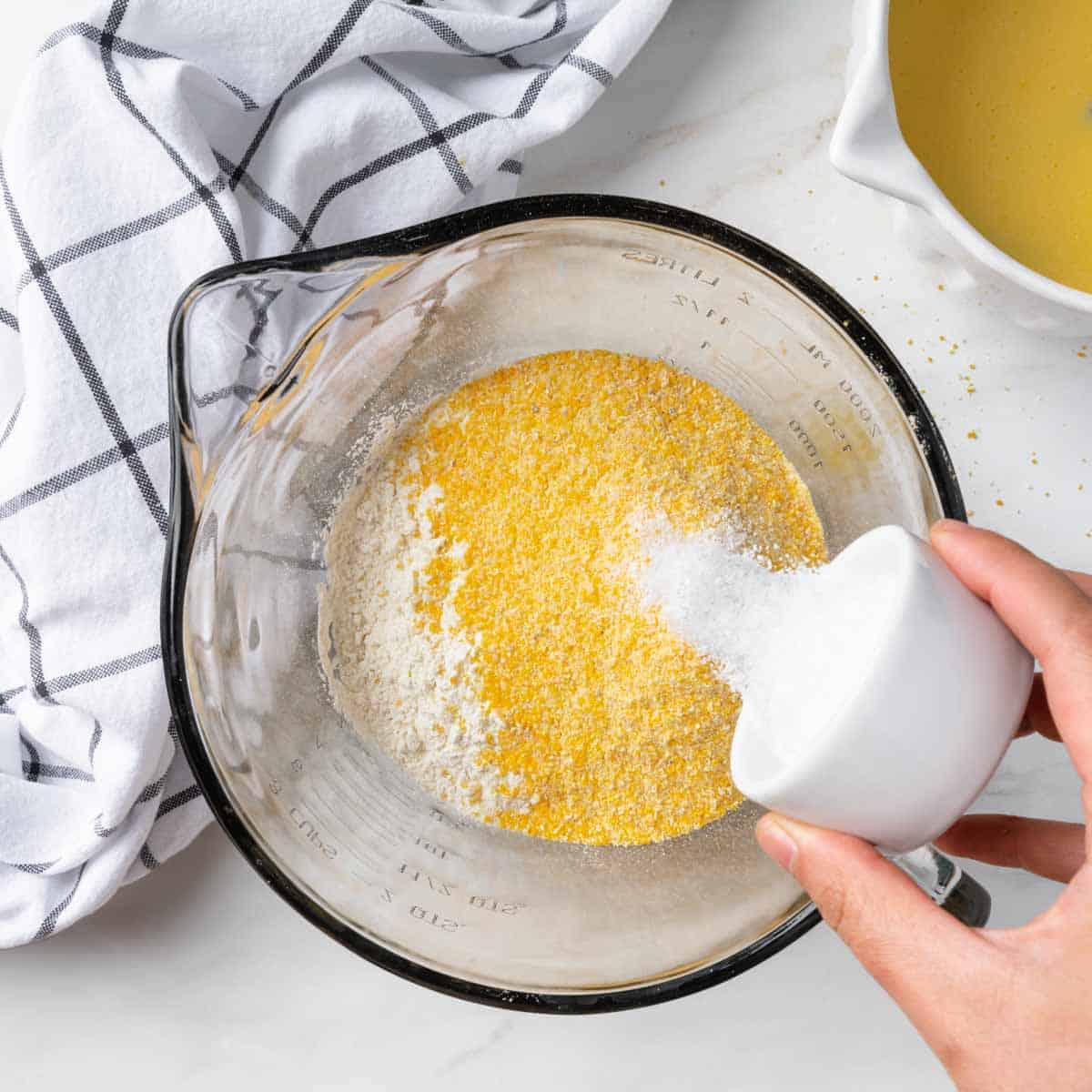Pouring salt into a big bowl of flour and cornmeal