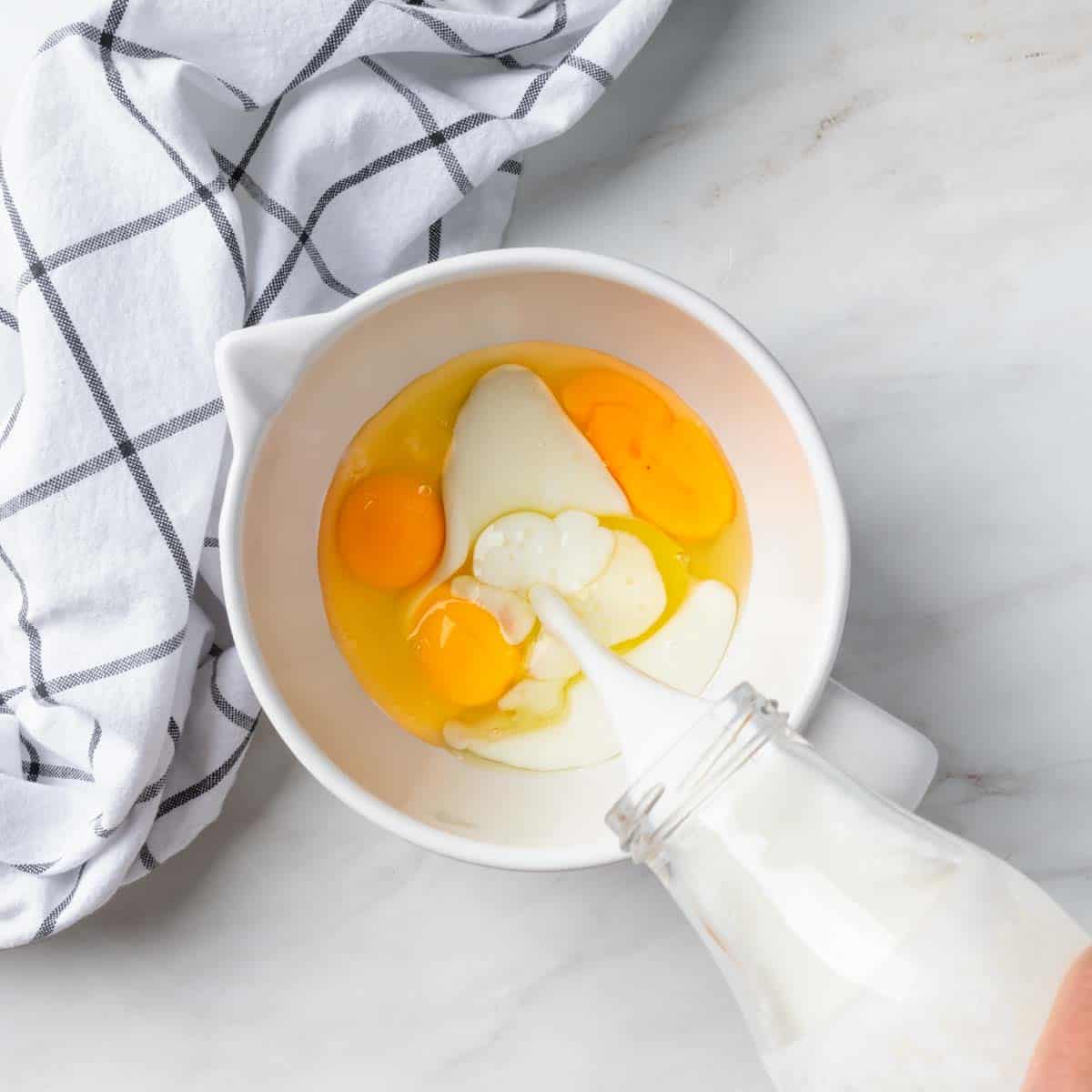 Pouring buttermilk into a bowl of eggs