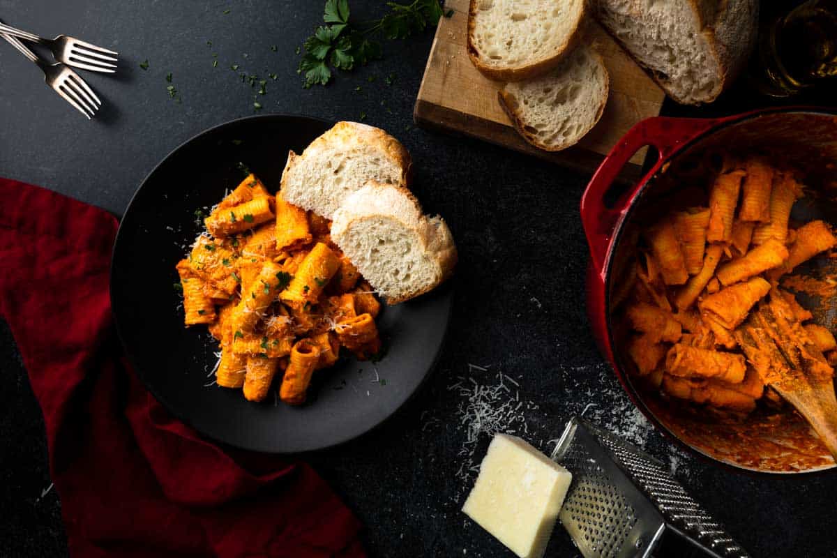 A table with a big serving of 'Nduja pasta, grated cheese and bread