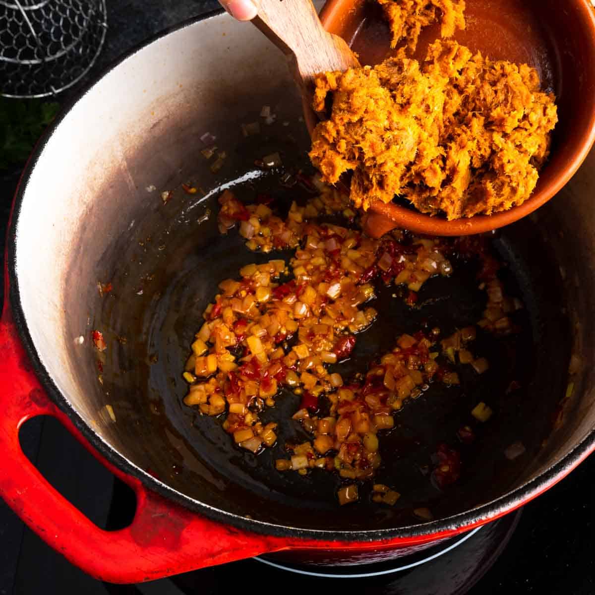 Adding 'nduja sausage to the pot